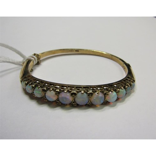 202 - A 9ct gold bangle set with eleven graduated opals - 23g overall.