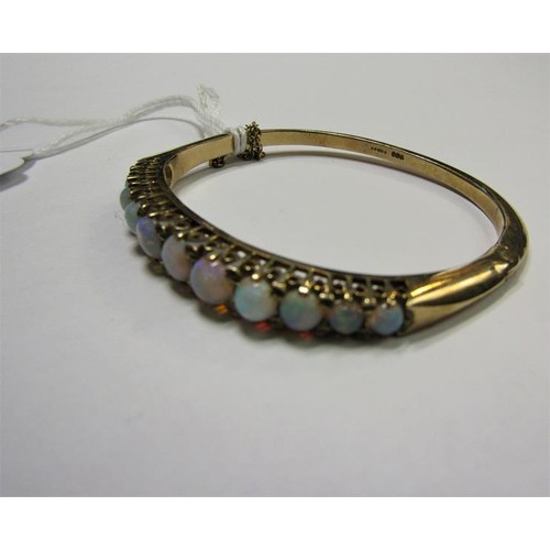 202 - A 9ct gold bangle set with eleven graduated opals - 23g overall.