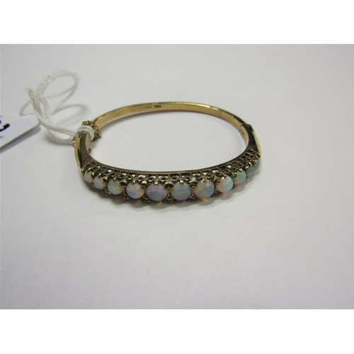 202 - A 9ct gold bangle set with eleven graduated opals - 23g overall.