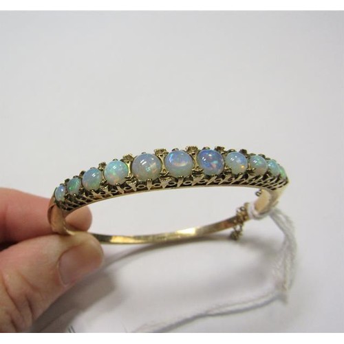 202 - A 9ct gold bangle set with eleven graduated opals - 23g overall.