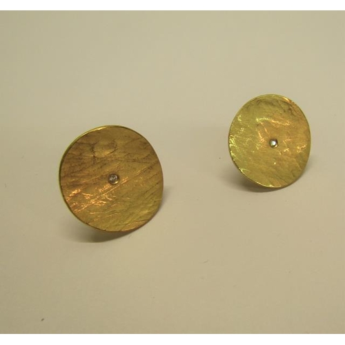 128 - A pair of Obelle 22ct gold earrings of circular beaten design, each with a central solitaire diamond... 