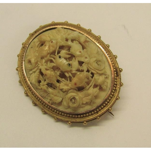 135 - A Victorian gilt metal brooch carved in high relief with a crab surrounded by fish within a rose bor... 