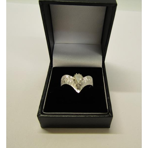 140 - A 1950's 18ct white gold ring set with a cut pear shaped diamond within a barked effect wishbone, ap... 