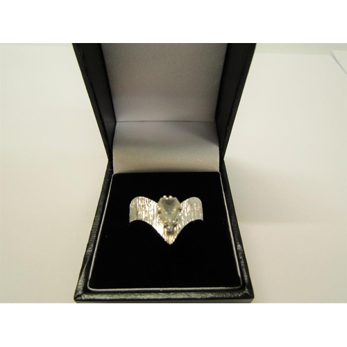 140 - A 1950's 18ct white gold ring set with a cut pear shaped diamond within a barked effect wishbone, ap... 