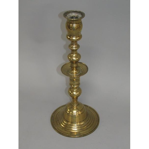 22 - An 18c bronze bell base candlestick with a double knopped column with central drip pan and having a ... 