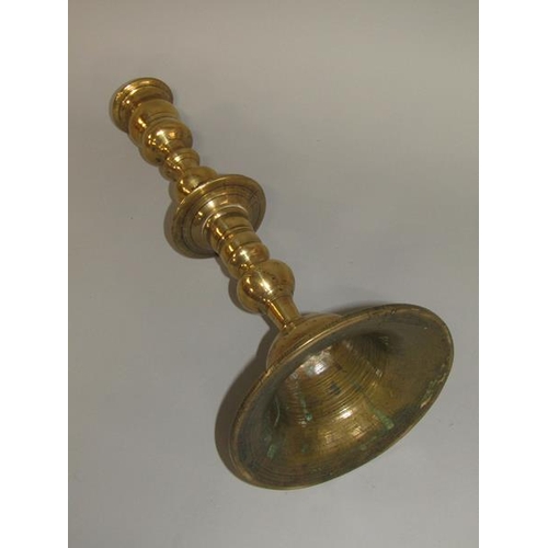 22 - An 18c bronze bell base candlestick with a double knopped column with central drip pan and having a ... 