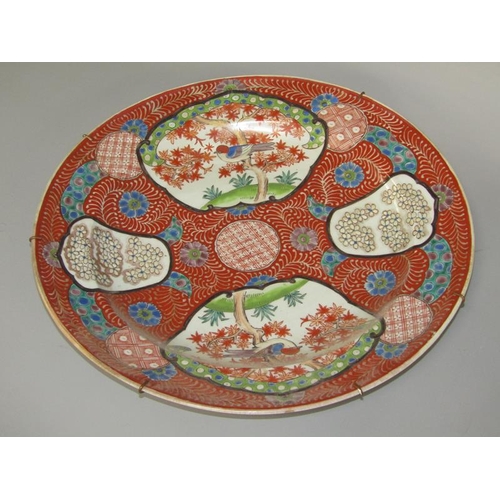 262 - A Meiji period Imari pattern charger decorated in red with birds in blossom and blossom panels, with... 