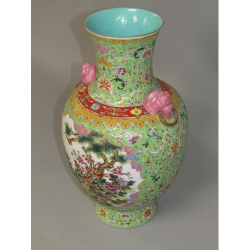 265 - A Chinese Republican period baluster vase of green floral pattern ground, having two pink glazed lio... 