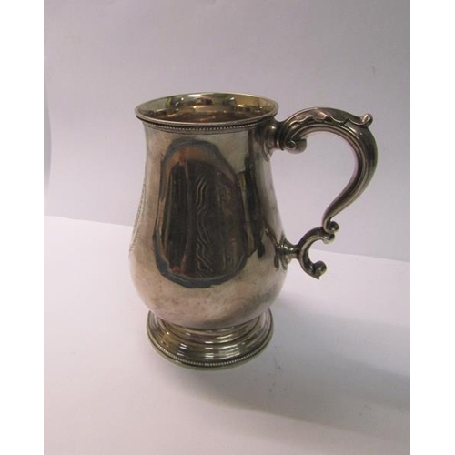 225 - A late Victorian tankard of baluster form with a double scroll handle, beaded upper rim and supporte... 