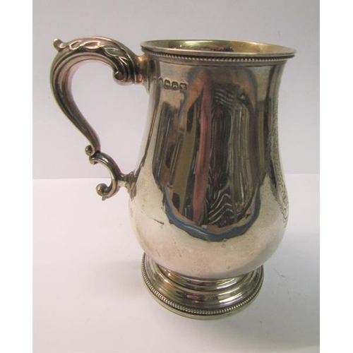 225 - A late Victorian tankard of baluster form with a double scroll handle, beaded upper rim and supporte... 