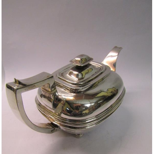 234 - A George II silver teapot of compressed bulbous ribbed form with angular handle and supported on fou... 