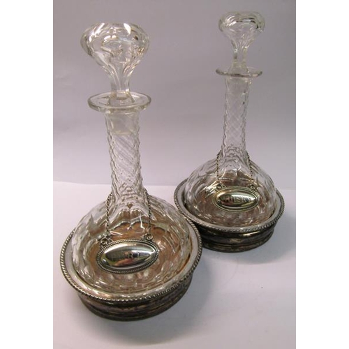 247 - A pair of late Victorian cut glass decanters and stoppers together with silver plated bottle tickets... 