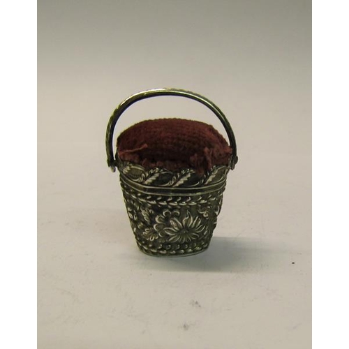 176 - A Victorian silver pin cushion in the form of a floral embossed bucket with swing handle, marks rubb... 