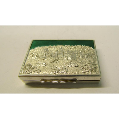 179 - A silver and enamel snuff box with a castle top hinged cover, having a green enamel sky, gilt lined ... 