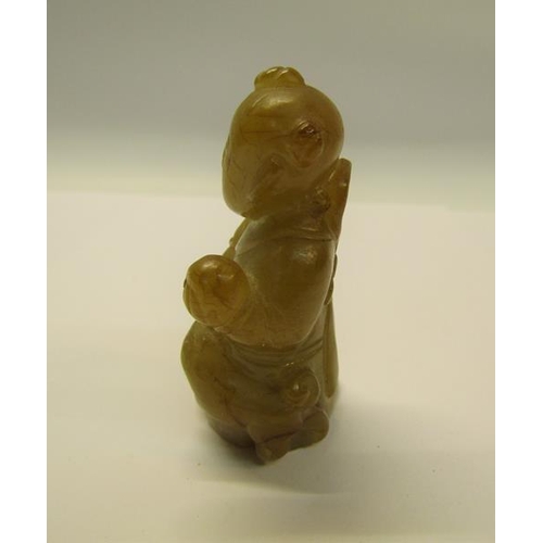 72 - A 17c Chinese mutton fat jade figure with slight brown striations, modelled as a seated monk with a ... 