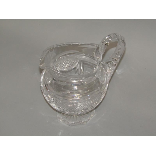 249 - An early 19c English cut glass jug with diamond cut and swag decoration, scrolling handle, supported... 