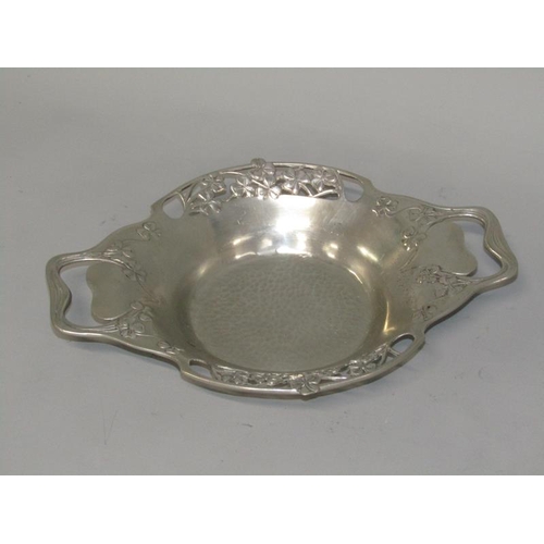 41 - An Art Nouveau pewter two handled bowl with beaten base, floral pierced borders and with two side ha... 