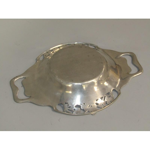 41 - An Art Nouveau pewter two handled bowl with beaten base, floral pierced borders and with two side ha... 