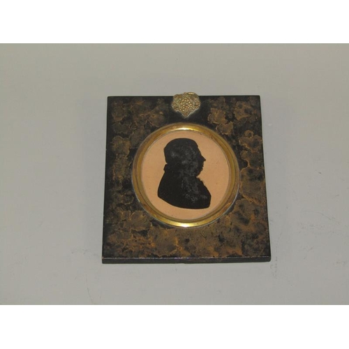 86 - An early 19c miniature silhouette on glass of a gentleman, oval framed in ebonised and gilt leaf dec... 