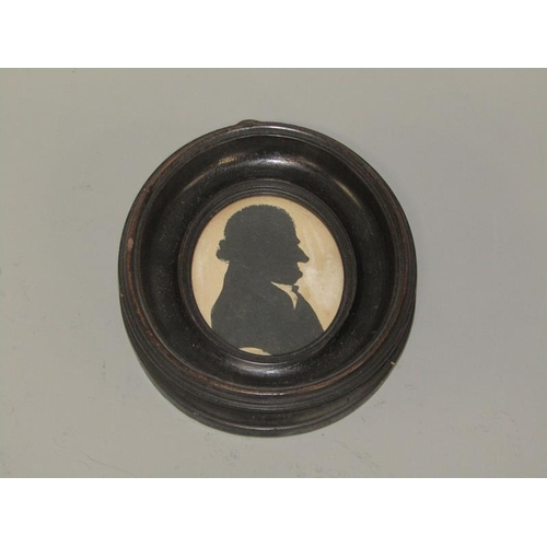 86 - An early 19c miniature silhouette on glass of a gentleman, oval framed in ebonised and gilt leaf dec... 