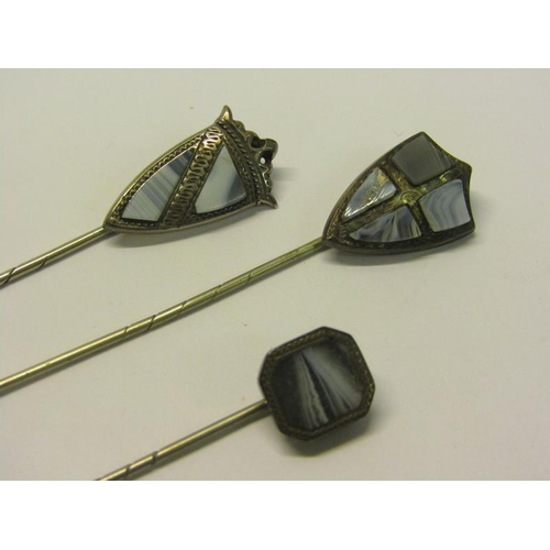 144 - A collection of three early 20c white metal stick pins, two of shield shaped form, all set with gree... 