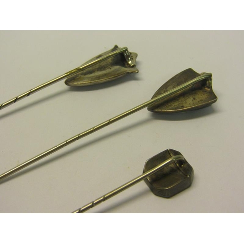 144 - A collection of three early 20c white metal stick pins, two of shield shaped form, all set with gree... 