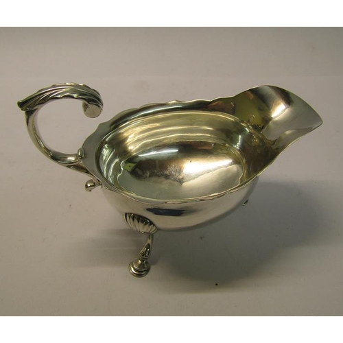 191 - A George II silver sauce boat with open scrolling handle, supported on three legs with hoof feet, ma... 