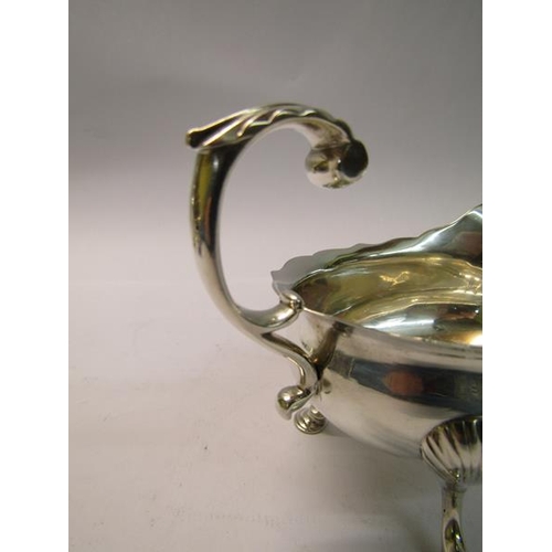 191 - A George II silver sauce boat with open scrolling handle, supported on three legs with hoof feet, ma... 