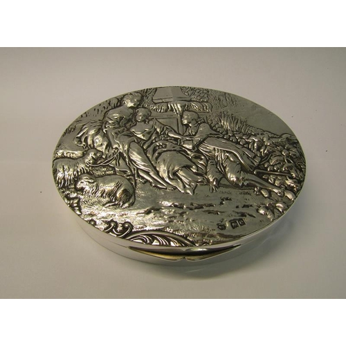 195 - A late Victorian silver ladies box of oval form, the hinged cover embossed and chased with a scene o... 