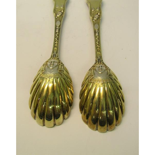 204 - A pair of late Victorian silver gilt serving spoons with shell shaped bowls, the handles cast with c... 