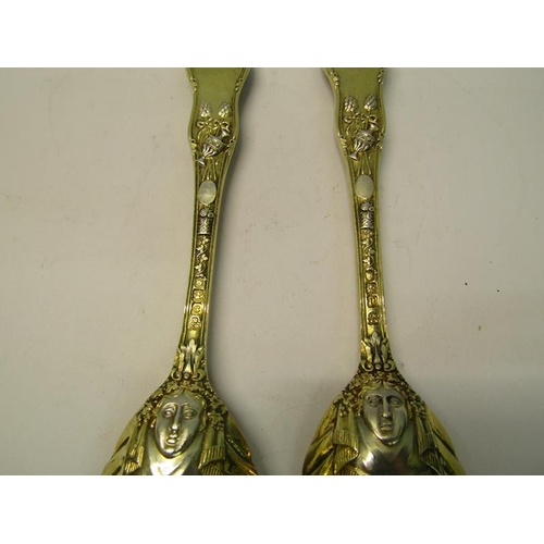 204 - A pair of late Victorian silver gilt serving spoons with shell shaped bowls, the handles cast with c... 