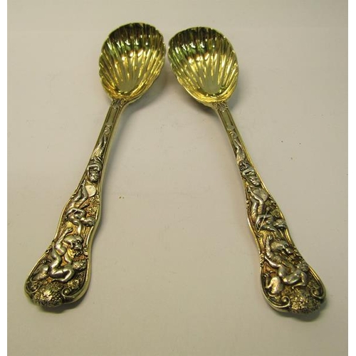 204 - A pair of late Victorian silver gilt serving spoons with shell shaped bowls, the handles cast with c... 