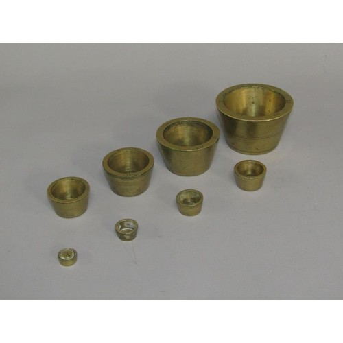 35 - A set of 19c brass cup weights, graduated in troy ounces from 18 to 1 1/4oz. 7cm diam, 4.25cm h.