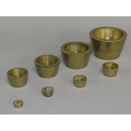 35 - A set of 19c brass cup weights, graduated in troy ounces from 18 to 1 1/4oz. 7cm diam, 4.25cm h.