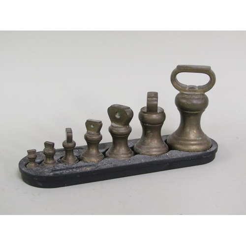 1240 - TWO SETS OF WEIGHTS IN CAST IRONS STANDS, LARGEST STAND 20CM L