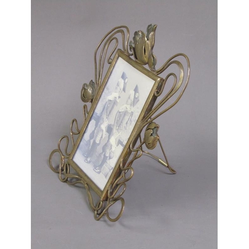 29 - An Art Nouveau brass easel photograph frame with an open scrolling floral mount, 25cm h, 20cm w over... 