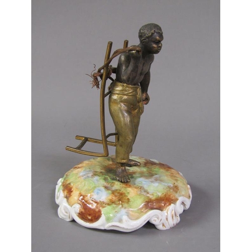 74 - A late 19c patinated metal figure of a West Indian bale carrier supported on a ceramic plinth, figur... 