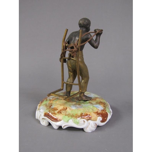 74 - A late 19c patinated metal figure of a West Indian bale carrier supported on a ceramic plinth, figur... 