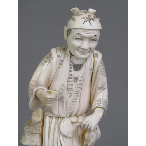 83 - A Japanese Meiji period carved ivory figure of a gentleman carrying two fish, base with incised sign... 