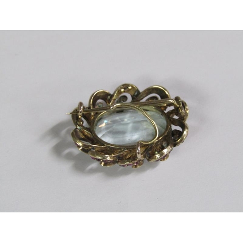 120 - A late 19c/early 20c aquamarine brooch, the central stone surrounded by a border of rubies and diamo... 