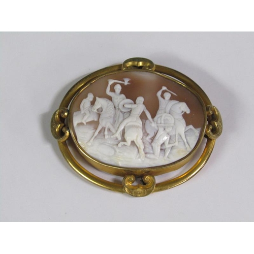 134 - A late 19c/early 20c shell cameo brooch of oval form depicting a battle scene on horse back, in a gi... 