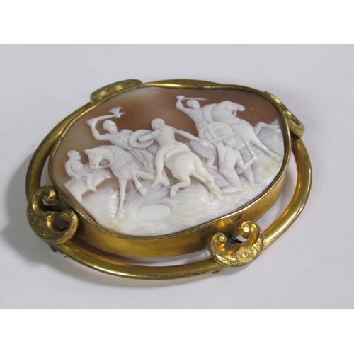 134 - A late 19c/early 20c shell cameo brooch of oval form depicting a battle scene on horse back, in a gi... 