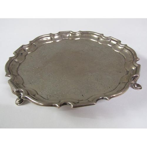 203 - A George II silver card tray of circular form with a raised and shaped border, supported on three ho... 