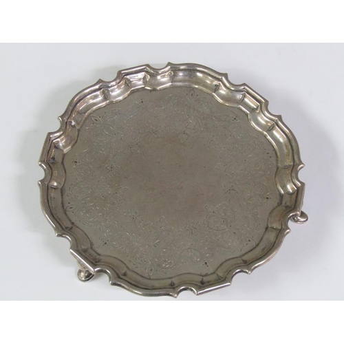 203 - A George II silver card tray of circular form with a raised and shaped border, supported on three ho... 