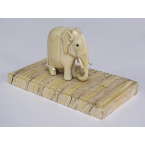72 - A 19c carved ivory elephant supported on a carved mammoth tooth, 8cm x 4cm.