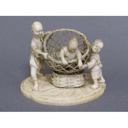 82 - A Japanese Meiji period ivory figure group of a lady and gentleman holding aloft a basket containing... 