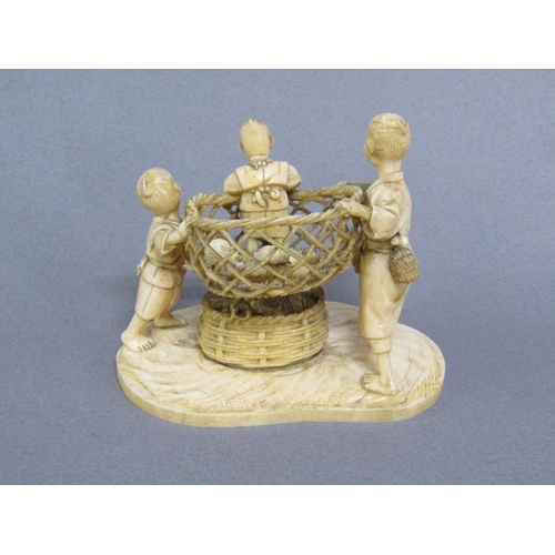 82 - A Japanese Meiji period ivory figure group of a lady and gentleman holding aloft a basket containing... 