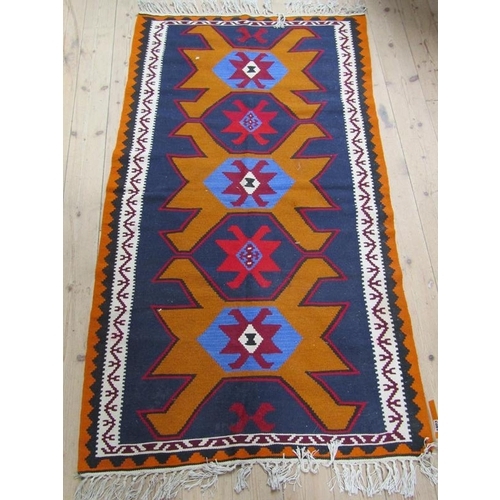 1803 - ORIENTAL RUG OF GEOMETRIC PATTERN BEING ORANGE BLUE AND FAWN GROUND 175 x 99 cms