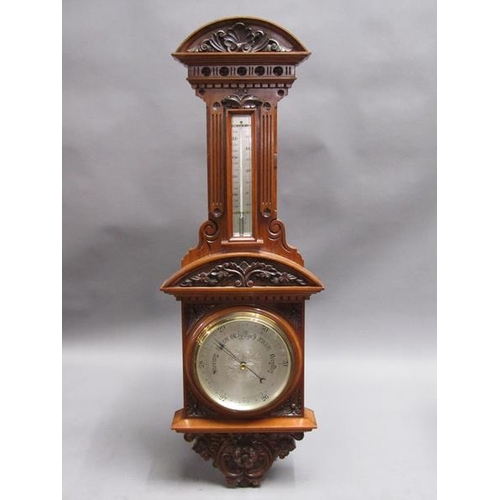 36 - An early 20c aneroid wall barometer, with 20cm diam. silvered dial set into a large heavily carved w... 