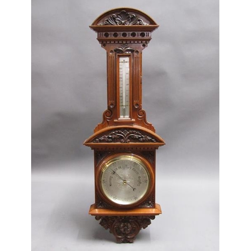 36 - An early 20c aneroid wall barometer, with 20cm diam. silvered dial set into a large heavily carved w... 